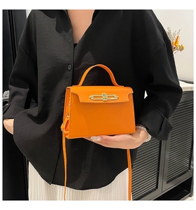 Detail of orange leather handbag showing gold bar buckle and round top handle