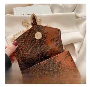 Close-up of golden magnetic clasp and brown snakeskin texture on mini flap bag
