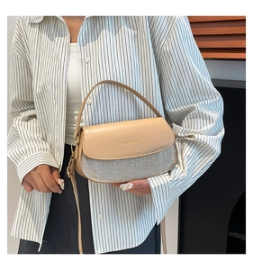 Shoulder bag with beige leather flap and silver sequin base shown on a model