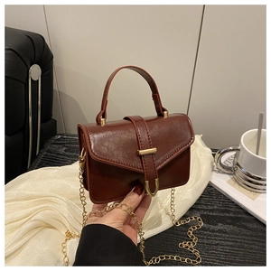 Close-up of a vintage dark brown leather crossbody bag with elegant gold U-shaped buckle