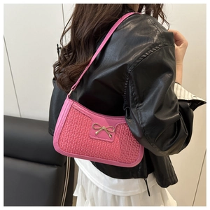 Détail du sac baguette tressé rose avec un nœud doré et une fine bandoulière élégante