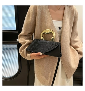 Chic black crocodile embossed bag with irregular gold handle shown on a model