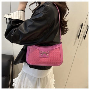 Gros plan du sac à bandoulière rose fuchsia avec texture cœur tissée et boucle nœud doré