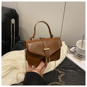 Detail view of a vintage brown PU leather handbag with a gold U-shaped buckle closure