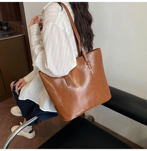 Detail of a large brown oil-wax leather tote bag worn on shoulder for daily commute