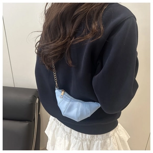 Détail du sac croissant bleu clair avec design plissé et fine chaîne dorée