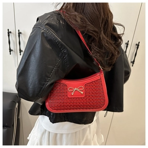 Détail du sac bandoulière rouge avec texture tissée et boucle en métal nœud doré