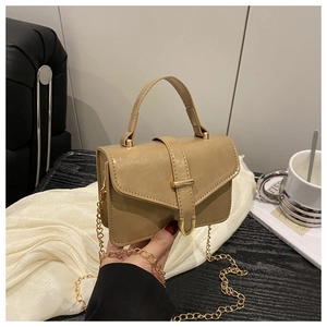 Detailed view of khaki crossbody bag with gold hardware and silk background