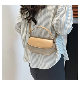 Detail of khaki textured box bag featuring gold lettering and contrasting panels