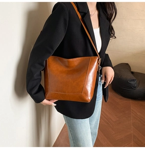 Close-up of brown wax leather tote bag with stylish stitching detail on a model