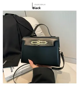 Close-up of elegant black leather handbag with a sleek golden bar metal clasp detail