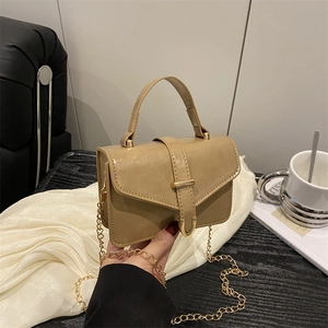 Minimalist light brown leather handbag with gold buckle and chain strap in hand