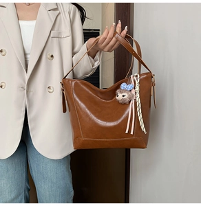 Brown oil wax leather tote bag shown with hedgehog charm on a model during commute
