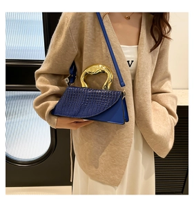 Dettaglio della borsa blu navy con motivo a coccodrillo e manico in metallo dorato