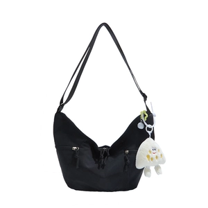 Minimalist black nylon crescent tote bag with utility pockets and plush charm pendant