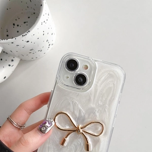 Detailed view of phone case featuring pearlescent white texture and golden metal bow