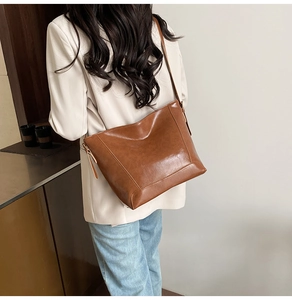 Detailed back view of a large brown leather tote bag worn by a model in a beige suit