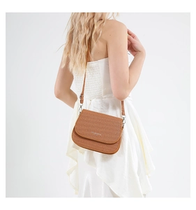 Detailopname van bruine getextureerde crossbodytas met Fashion Trends logo aan zijkant