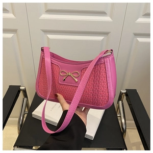 Détail d'un sac à main rose tissé avec un nœud en métal doré et une poignée en cuir