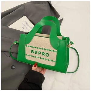 Detail view of the green leather handbag featuring white canvas patchwork and BEPRO embroidery