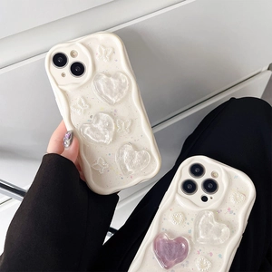 Detail of cream wavy iPhone 16 case with 3D resin heart, bow, and sparkling glitter