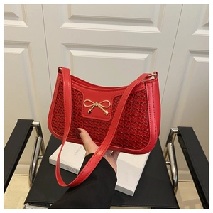 Détail du sac rouge en forme de croissant avec texture tressée et boucle nœud doré