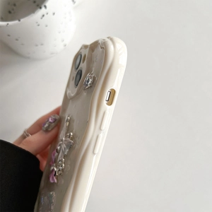 Detail of cream 3D wavy phone case with 3D bow and sparkling rhinestone accents