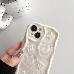 Detailed close-up of cream wavy iPhone case with 3D hearts, pearls and glitter finish