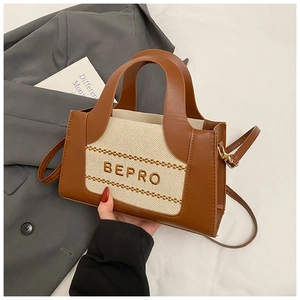 Detail of trendy tote bag showing beige canvas, brown leather stitching and BEPRO embroidery