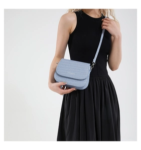 Close-up van lichtblauwe crossbody tas met denim textuur en zilveren gesp op het model
