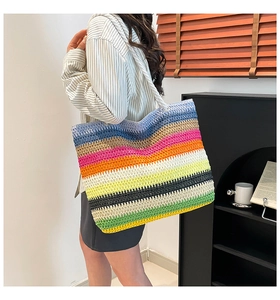 Détail d'un grand sac de plage tressé avec rayures arc-en-ciel et poignées en corde blanche