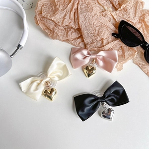 Bow phone grip set with metallic heart pendants in cream, pink, and black colors