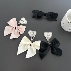 Close-up of heart-shaped rhinestone buckles and silk bow charms in pink, beige and black