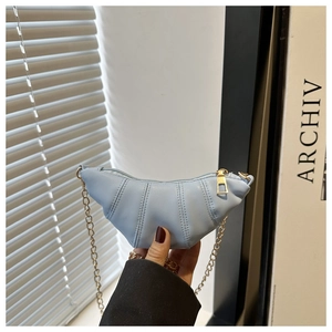 Close-up of a light blue croissant bag featuring quilted stitching and a gold chain strap