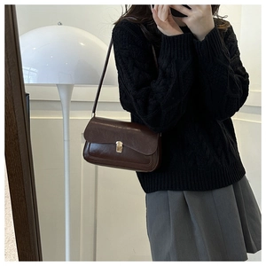 Retro dark brown leather shoulder bag with metallic lock shown on model with pleated skirt