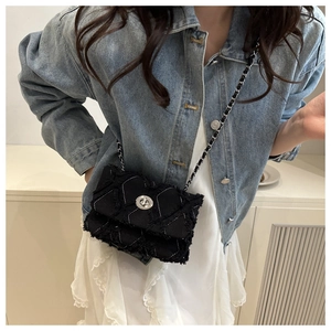 Détail du sac bandoulière en tweed noir avec motifs matelassés et bords effilochés