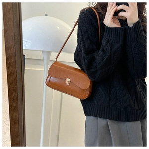 Detail of vintage brown leather underarm bag with gold square buckle on a model