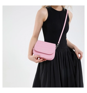 Roze minimalistische crossbody tas met zilveren logo gedragen door model in zwart