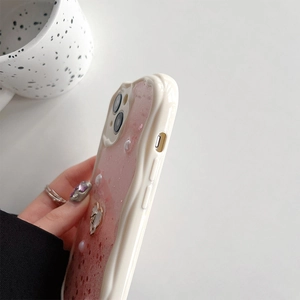 Dettaglio della custodia iPhone rosa glitterata con perle 3D, cuori e bordo crema ondulato