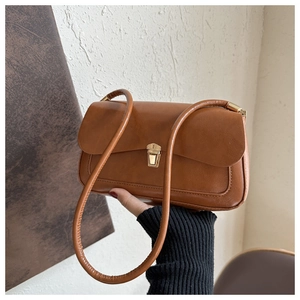Close-up of vintage brown shoulder bag featuring a refined gold metal clasp and thin strap