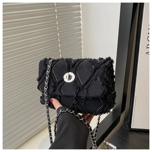 Détail du sac bandoulière en tweed noir avec fermoir argenté et texture effilochée