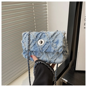 Détail du sac bandoulière en denim bleu clair avec coutures matelassées et franges