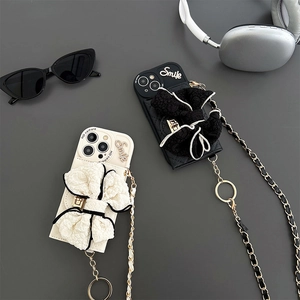 Detail of iPhone case with large fabric bow and crossbody metal chain on dark background