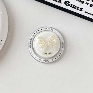 Detail of a creamy bow magnetic phone grip with Gift For You text on a round base