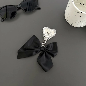Macro view of rhinestone heart charm with love engraving and black satin ribbon bow