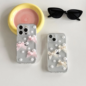 Coque iPhone transparente pailletée avec nœud en soie et perles blanches sur fond gris