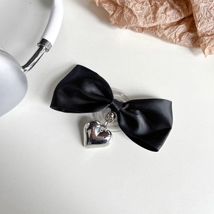 Detail of a black ribbon bow with a metallic silver heart pendant on a white surface