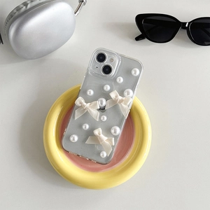 Détail de coque iPhone avec perles blanches et nœud en ruban sur fond pailleté