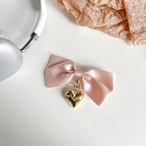 Detail of pink satin bow phone grip with a polished golden heart-shaped metal pendant