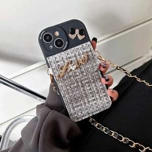 Detail of tweed phone case with rhinestone Love emblem, bow, and crossbody chain